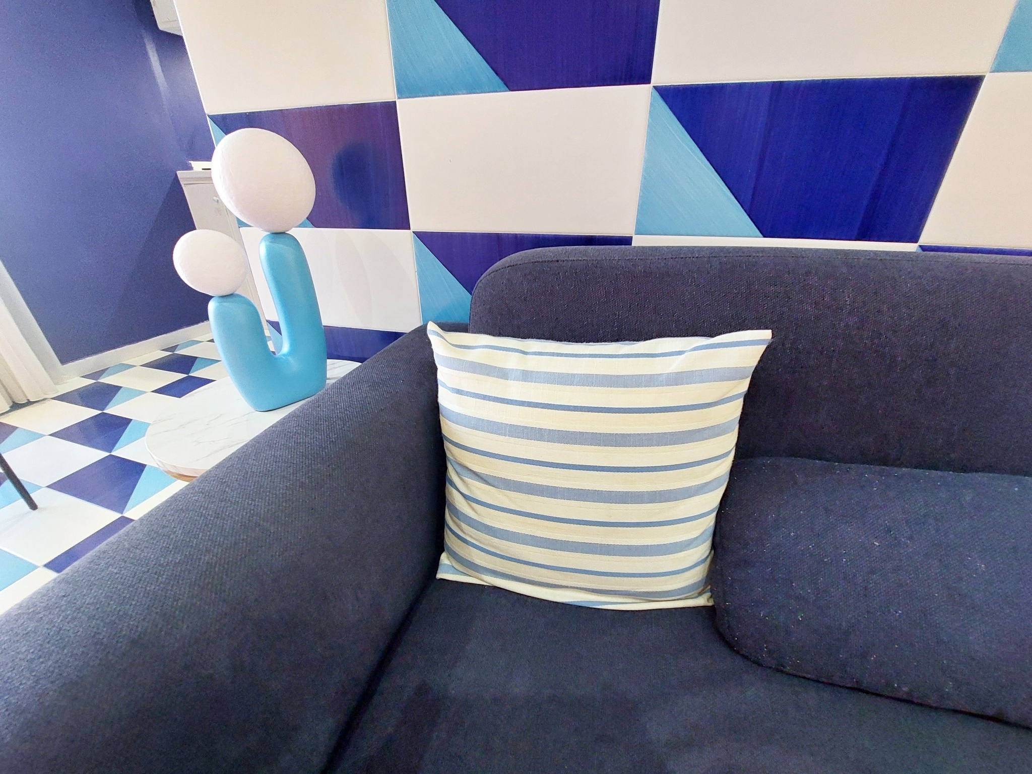 Sofa with striped cushion and turquoise lamp